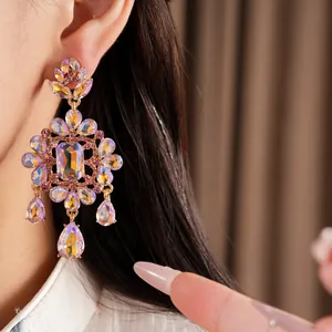 Close-up of ornate palace-style earrings with iridescent crystals and teardrop pendants.