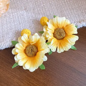 Detailed close-up of yellow raffia sunflower fabric drop earrings with natural textures