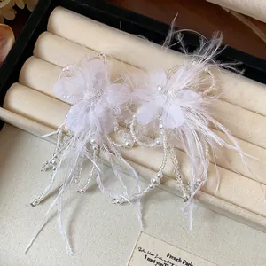 Detailed view of exquisite white feather flower earrings with delicate pearl tassels and beads.