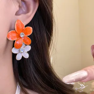 Close-up of vibrant orange and white drip oil flower earrings with sparkling rhinestones
