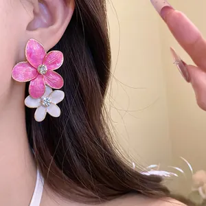 Close-up detail of rhinestone inlaid pink and white enamel flower pendant earrings.