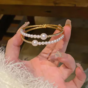 Detailed macro view of elegant gold bangles featuring lustrous pearls and sparkling crystals