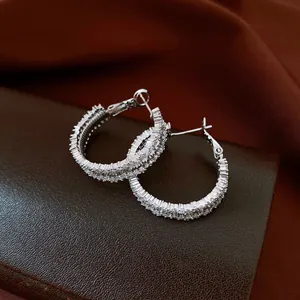 Dettaglio di orecchini a cerchio in argento con pavé di scintillanti zirconi bianchi.