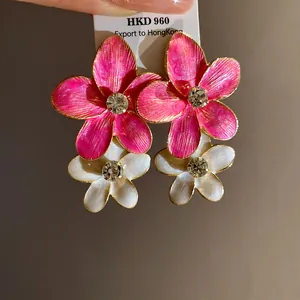 Detailed view of pink and white enamel flower earrings with sparkling rhinestone centers