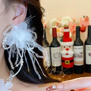 Close-up of elegant white feather and flower earring set with pearls on a model