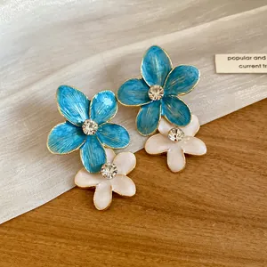Detailed close-up of blue and white enamel flower earrings with sparkling rhinestones