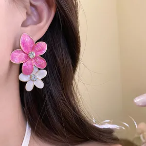 Close-up detail of vibrant pink and white oil-drop floral earrings with rhinestones
