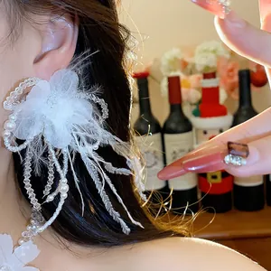 Close-up view of elegant white feather and floral earring with pearl tassels detail