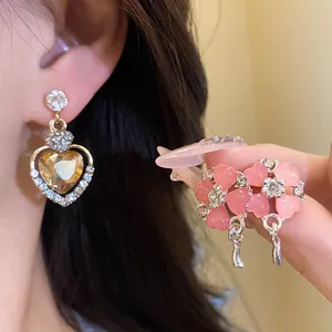 Dettaglio macro di eleganti orecchini a cuore in argento e fiori rosa con brillanti strass