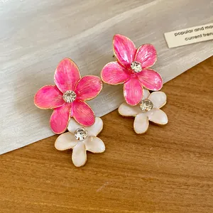Close-up detail of stylish pink and white enamel flower earrings with central rhinestones