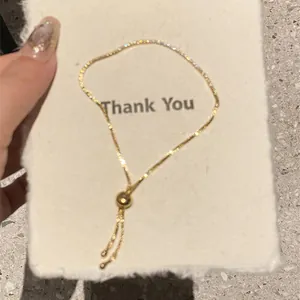 Detail view of 18k gold plated slider bracelet on a white textured card with gold bead