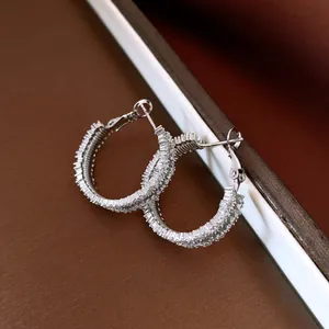 Dettaglio degli orecchini a cerchio in argento tempestati di zirconi lucidi