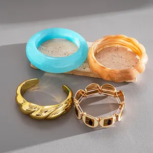 Collection détaillée de joncs en résine et de bracelets élastiques en émail doré.