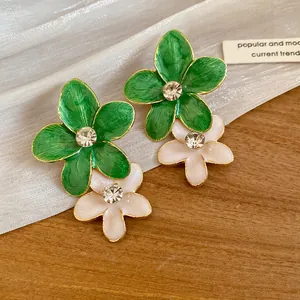 Close-up of green and white enamel flower earrings with sparkling rhinestone centers