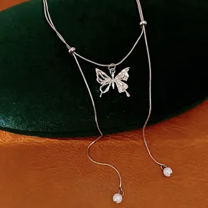 Elegant silver butterfly tassel necklace with pearl accents on a green velvet display.