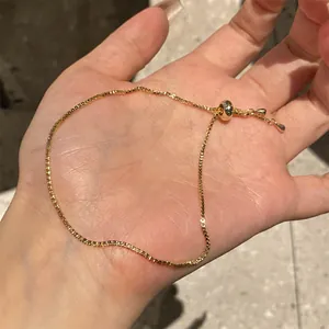 Detail view of gold-plated box chain bracelet with adjustable slider bead in hand