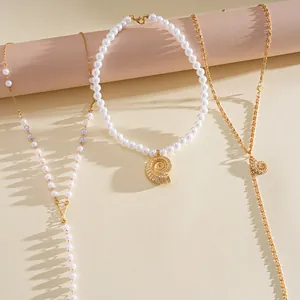 Detailed view of three-piece gold-tone necklace set with pearls and shell pendants