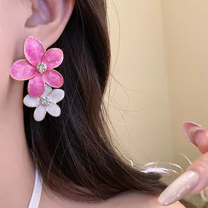 Detailed view of pink and white enamel flower earrings with crystal centers on model