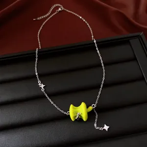 Close-up detail of silver chain necklace with glossy green apple pendant and star charms