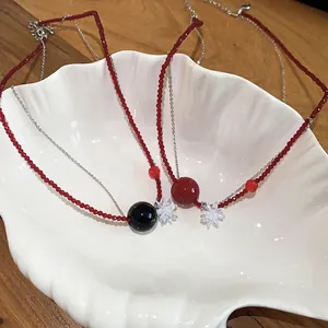Collana con perline di cristallo e ciondoli a fiore e sfera su vassoio a conchiglia