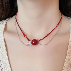 Collana a doppio strato con perle di cristallo rosso e un delicato ciondolo a forma di fiore