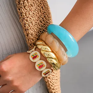 Gros plan de bracelets en émail colorés et joncs en résine avec détails dorés