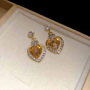 Dettaglio di orecchini a forma di cuore color ambra con diamanti in una scatola regalo