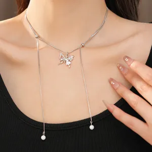 Detail shot of a silver butterfly pendant necklace with pearl tassels worn by a model