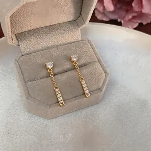 Minimalist gold plated earrings with sparkling zircons on jewelry box