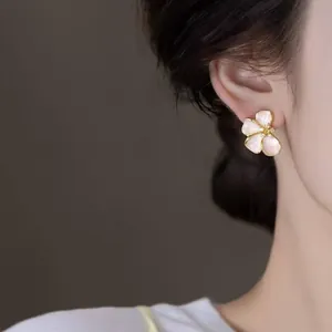 Detail shot of a French-style pink flower stud earring with rhinestone center on ear