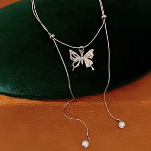 Detailed close-up of a silver butterfly necklace with double-layer chain and pearl accents.