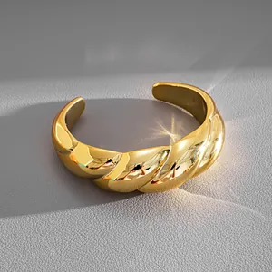 Vue détaillée d'un bracelet manchette torsadé en or poli avec une texture élégante