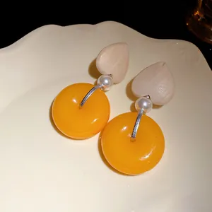 Detailansicht von Vintage-Ohrhängern mit Holzherz und orangefarbenem Harz-Donut-Anhänger