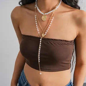 Detail view of layered pearl necklace with gold nautilus shell pendants for beach.