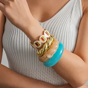 Vue détaillée de bracelets empilés en émail coloré et résine sur le bras d'un modèle