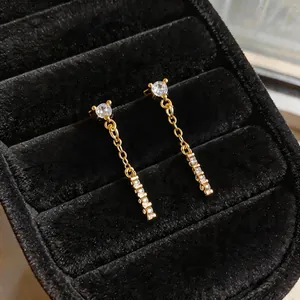 Macro detailed view of elegant gold tassel earrings featuring shimmering zircon stones.
