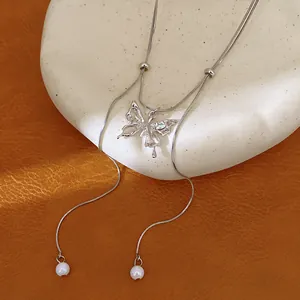 Detailed view of silver butterfly necklace with double chains and pearl tassels
