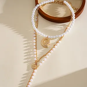 Detailed view of layered pearl necklace set with golden shell pendants for beach vacation