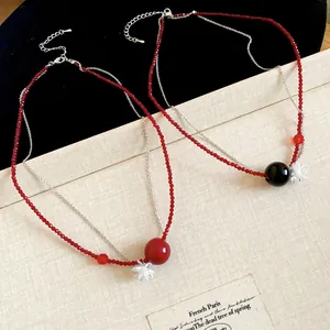 Dettaglio di collane di perle di cristallo rosso con perle nere e rosse e fiori