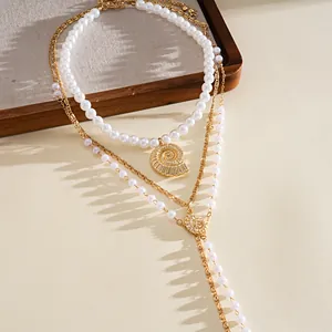 Detailed view of elegant triple-layered necklace featuring pearls and gold seashell pendant.
