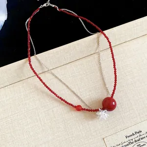 Dettaglio del colletto a doppio strato con perline di cristallo rosse e ciondolo