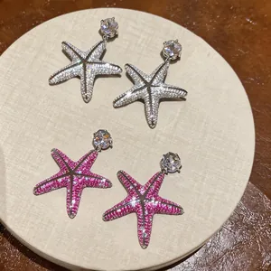 Primo piano di orecchini a lobo a forma di stella marina con zirconi rosa e argento