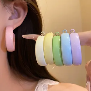 Detail of colorful spray-painted C-shaped hoop earrings in dopamine candy colors