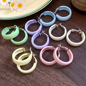 Detailed view of colorful spray-painted macaron hoop earrings on wooden background