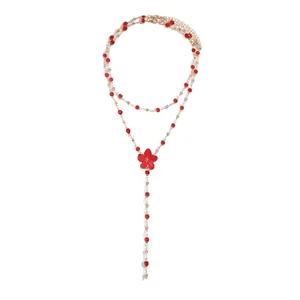 Elegant gold-tone lariat necklace featuring a red resin flower pendant and ruby-red accents