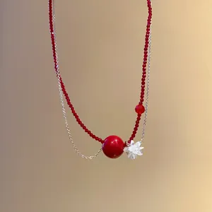 Dettaglio macro di perle di cristallo rosse e ciondolo a fiore su una collana