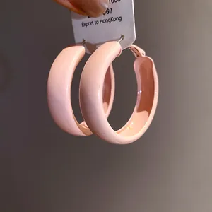 Macro view of minimalist pink spray-painted hoop earrings showing the smooth lacquer finish.