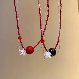 Dettaglio di collane di perle di cristallo rosse con ciondoli a fiore e perle tonde