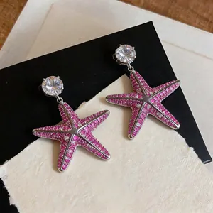 Primo piano squisito di orecchini a forma di stella marina in zircone rosa su sfondo
