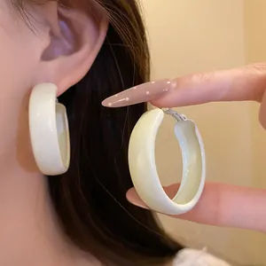 Close-up detail of cream beige spray-painted hoop earrings featuring a smooth matte finish